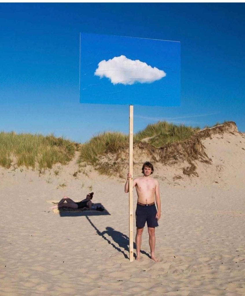 un homme sous un ciel bleu porte un panneau avec un beau nuage blanc